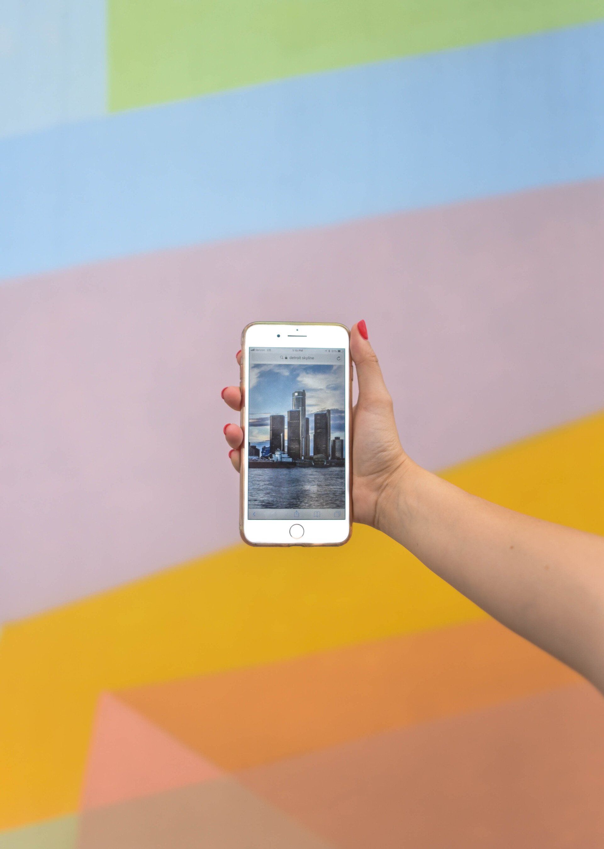 A person is holding a cell phone in front of a colorful wall