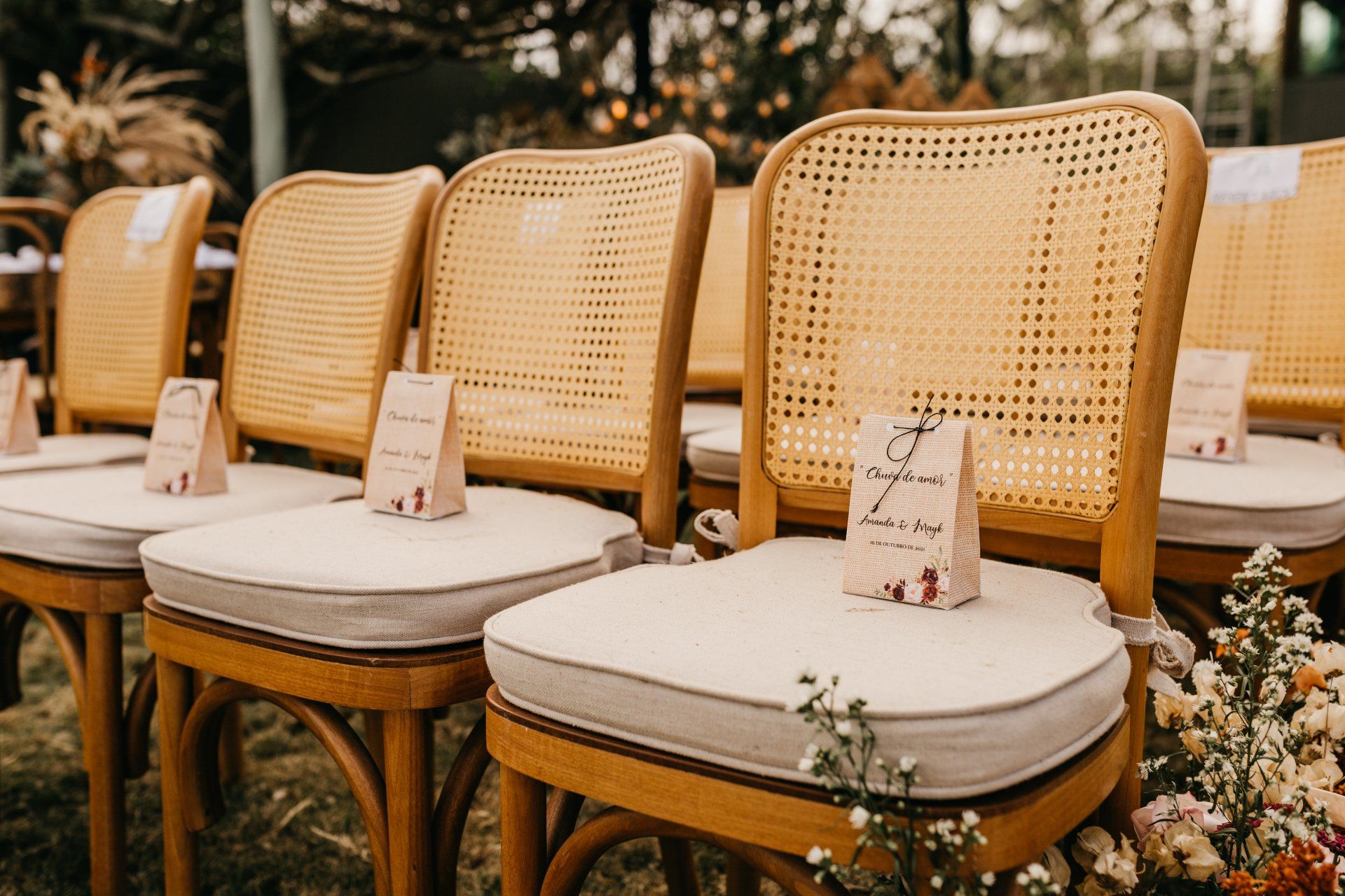 A row of wicker chairs are lined up in a row for a wedding ceremony.