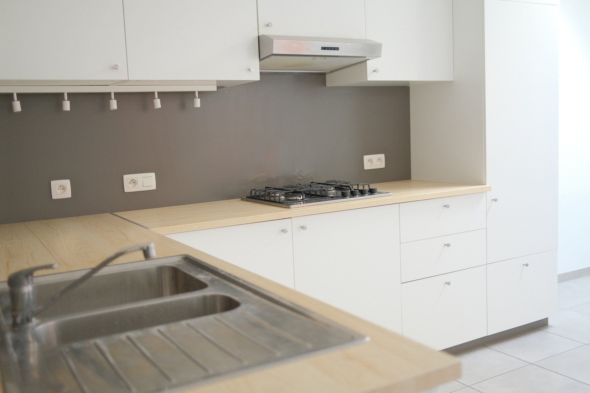 A kitchen with white cabinets , a sink , and a stove top oven.