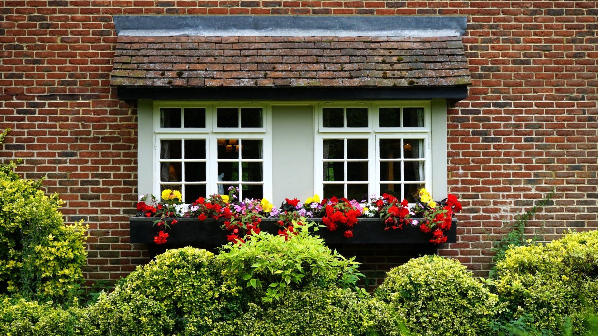 a brick house with a window with flowers in it