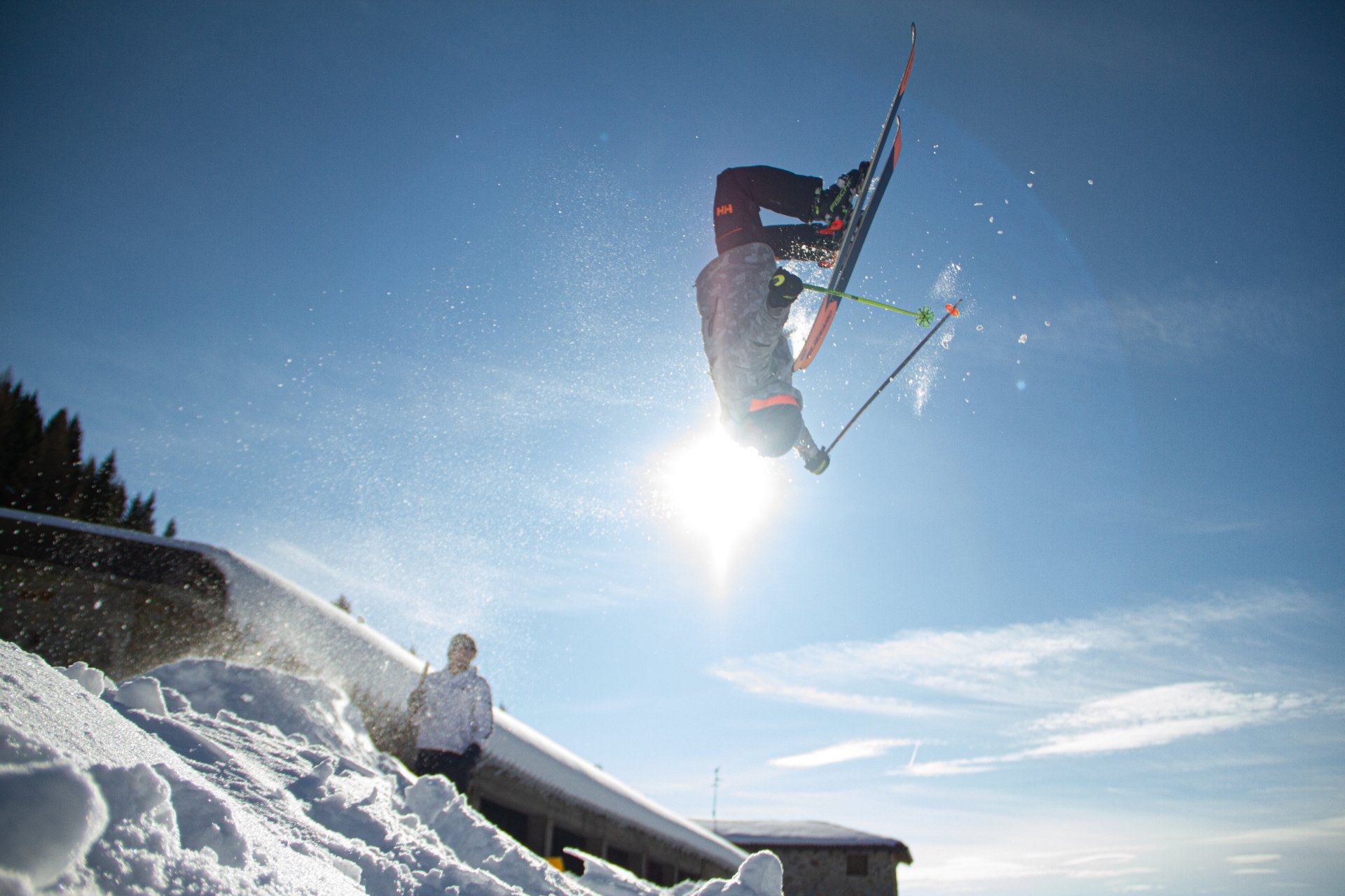 A person in a gray jacket freestyle skiing near a ski resort
