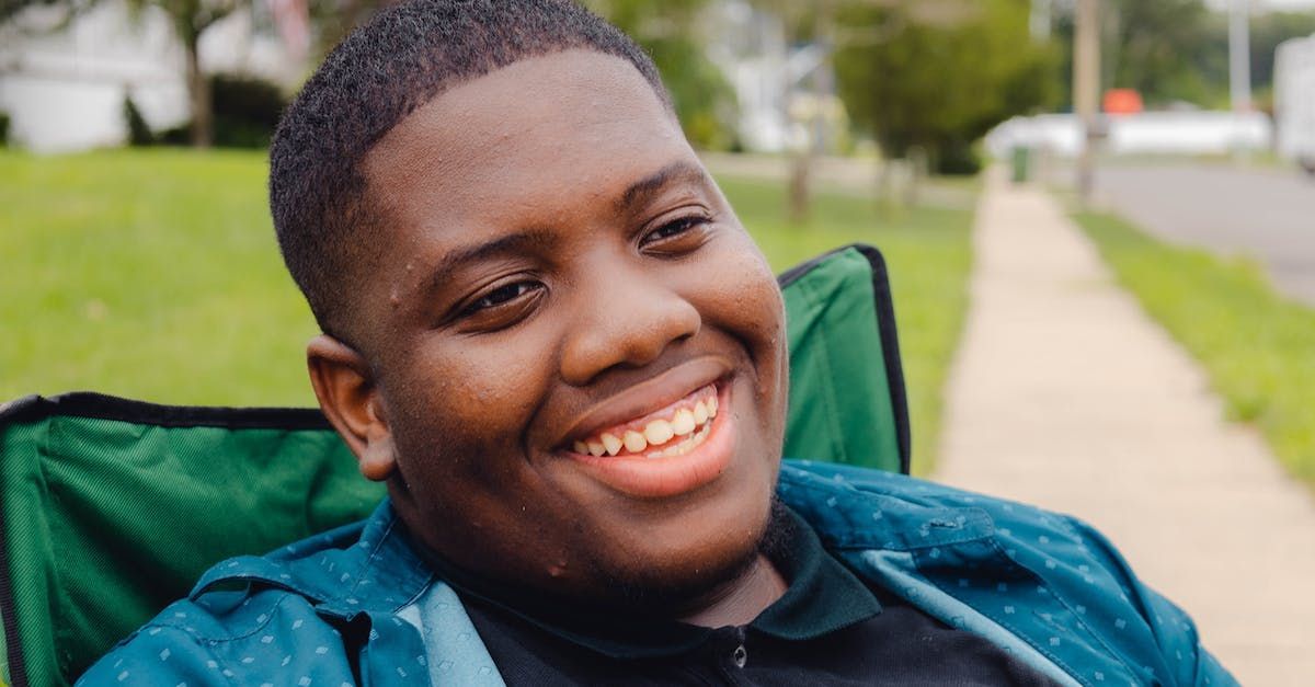 A young man is sitting in a green chair and smiling.