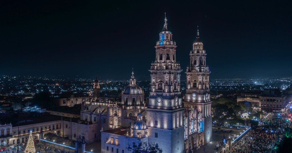 Una vista aérea de una catedral de noche con una ciudad al fondo.