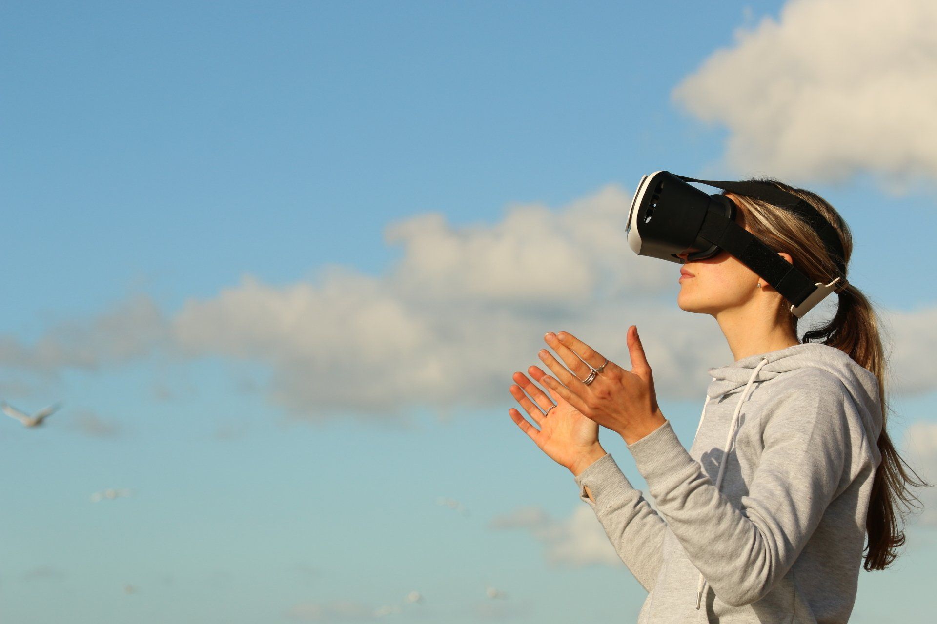 A woman wearing a virtual reality headset while standing on a beach