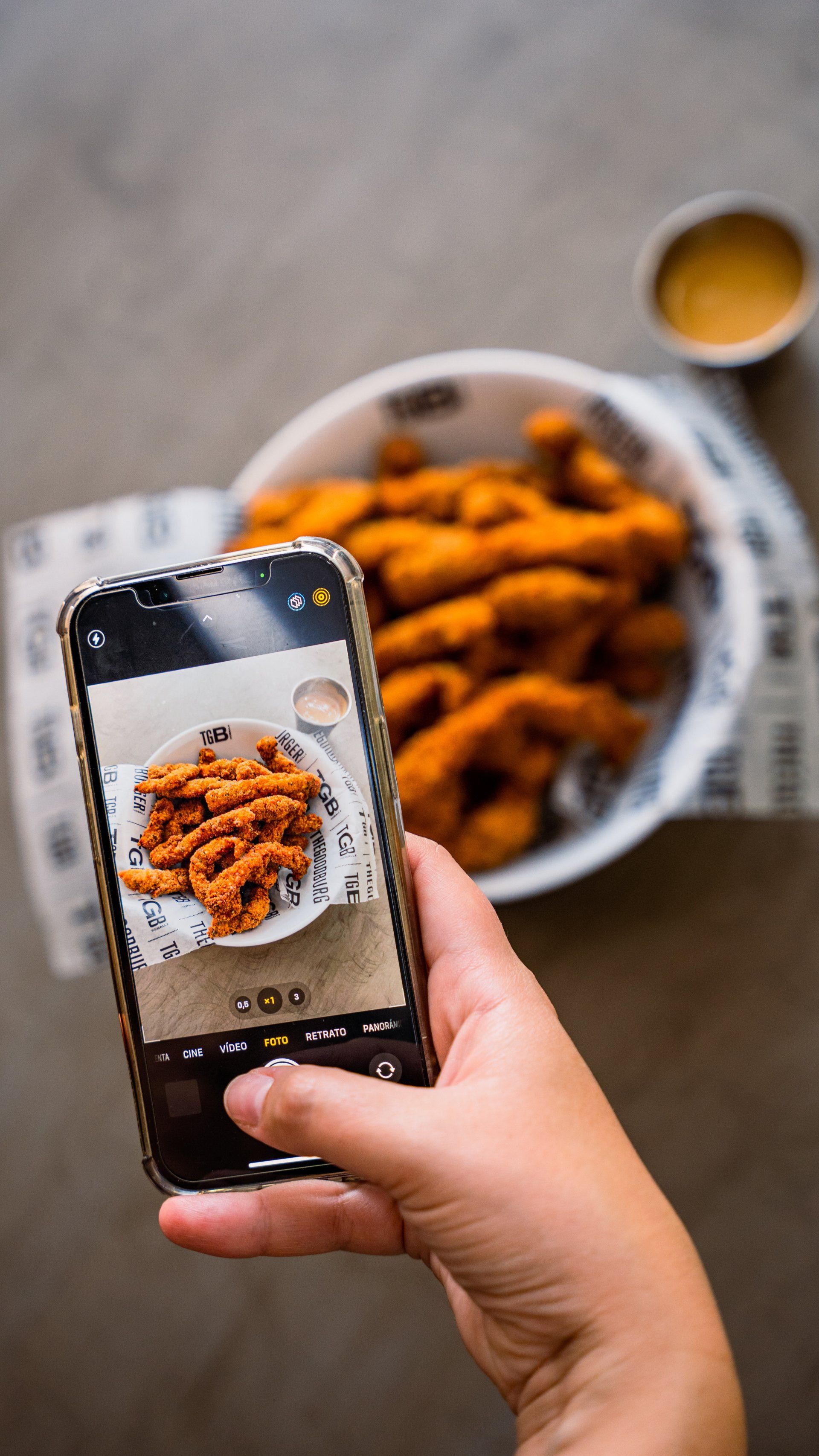 A person is taking a picture of a plate of food with a cell phone.