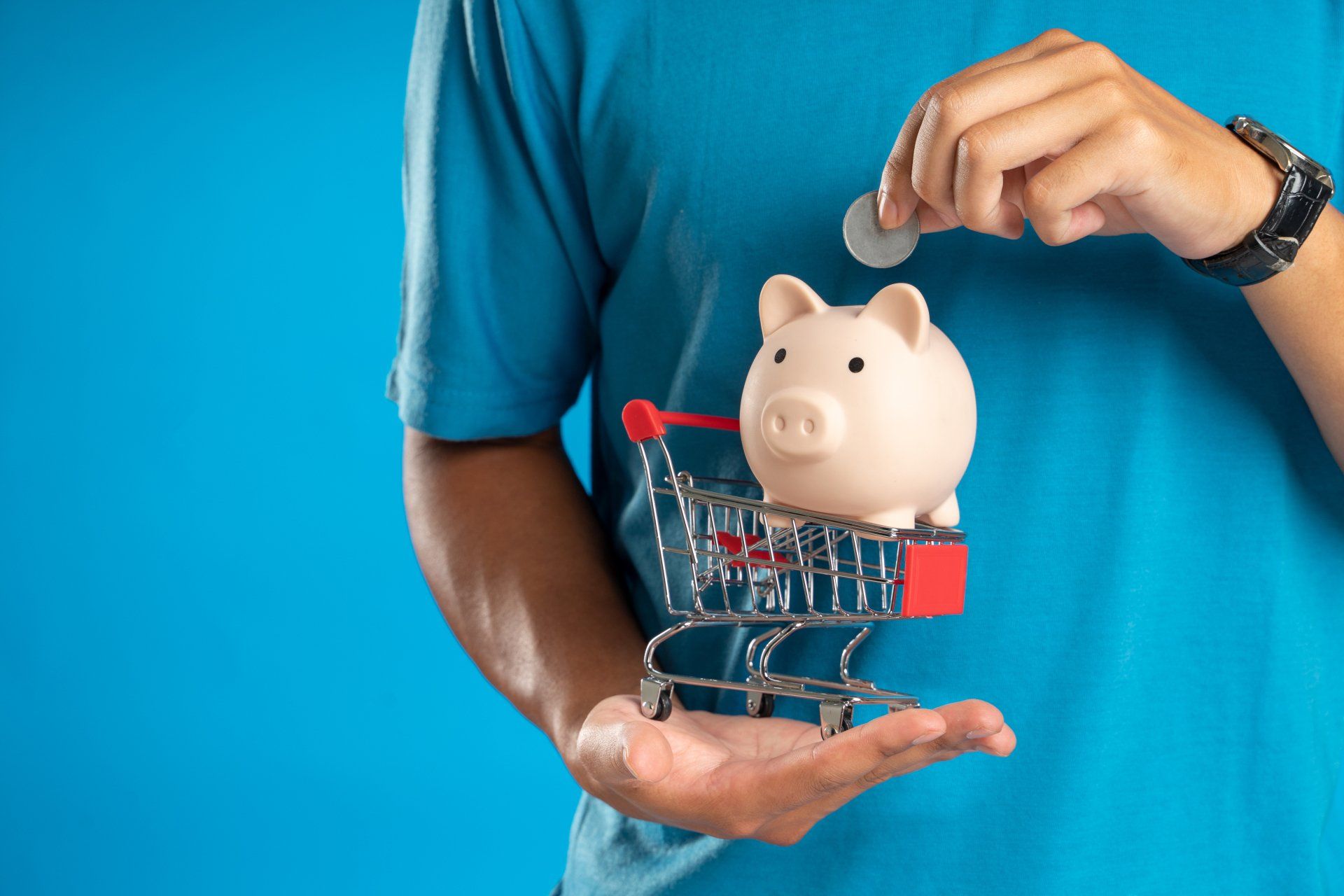 a man is putting a coin into a piggy bank in a shopping cart 