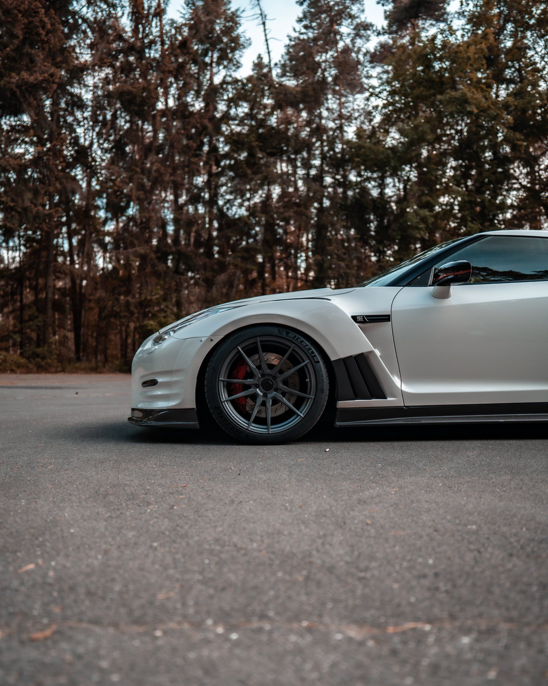 A white sports car is parked on the side of the road.