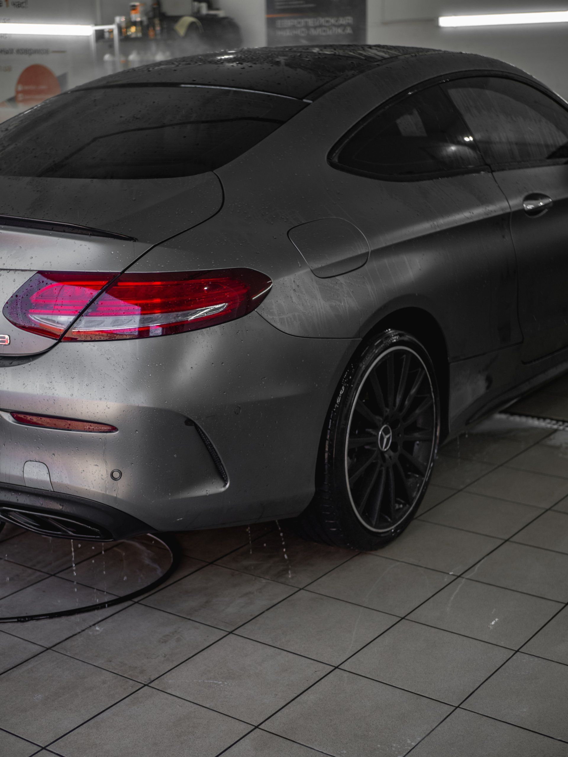 Ein graues Auto steht auf einem gefliesten Boden in einer Garage.