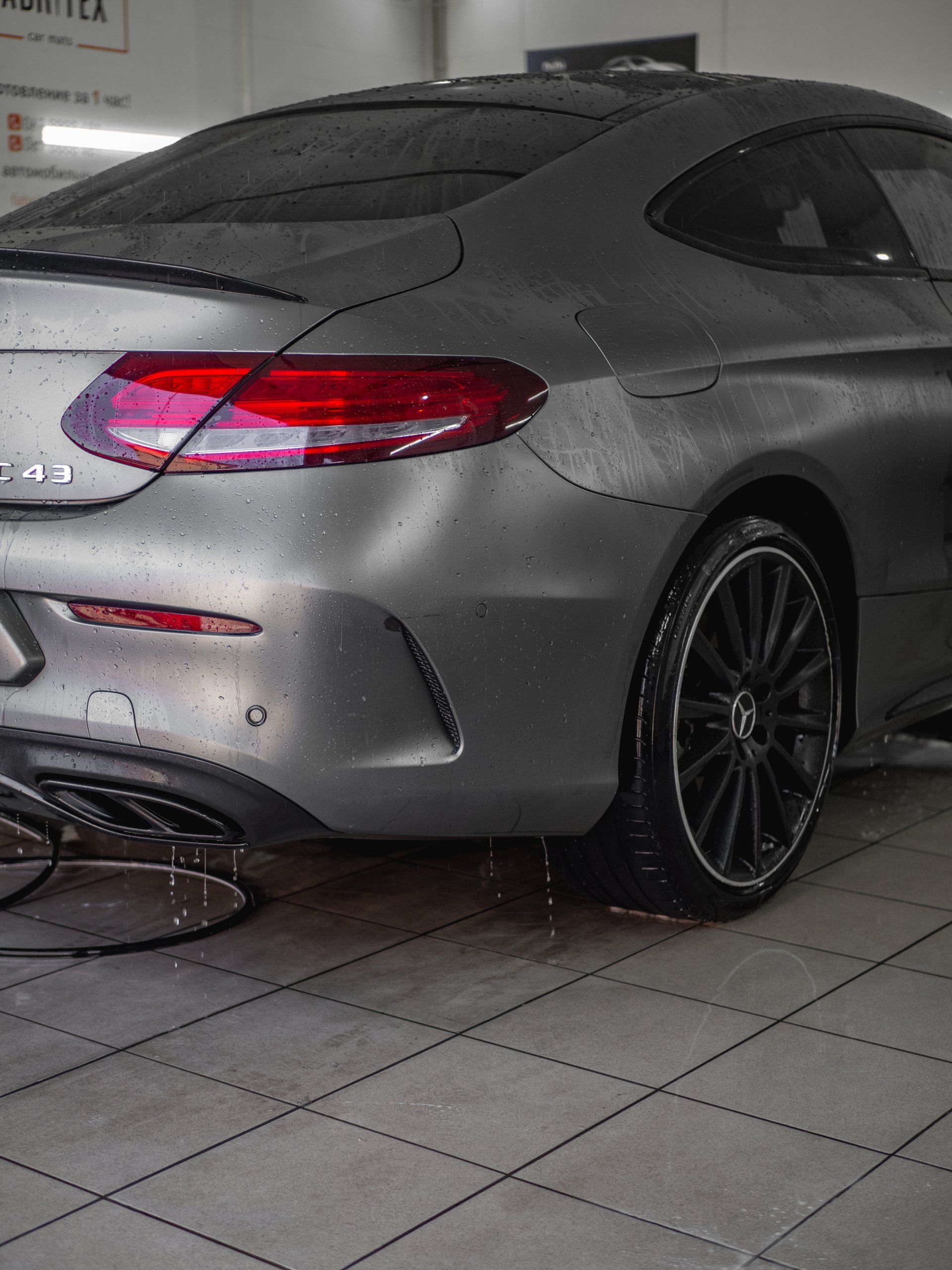 Ein silbernes Auto steht auf einem gefliesten Boden in einer Garage.