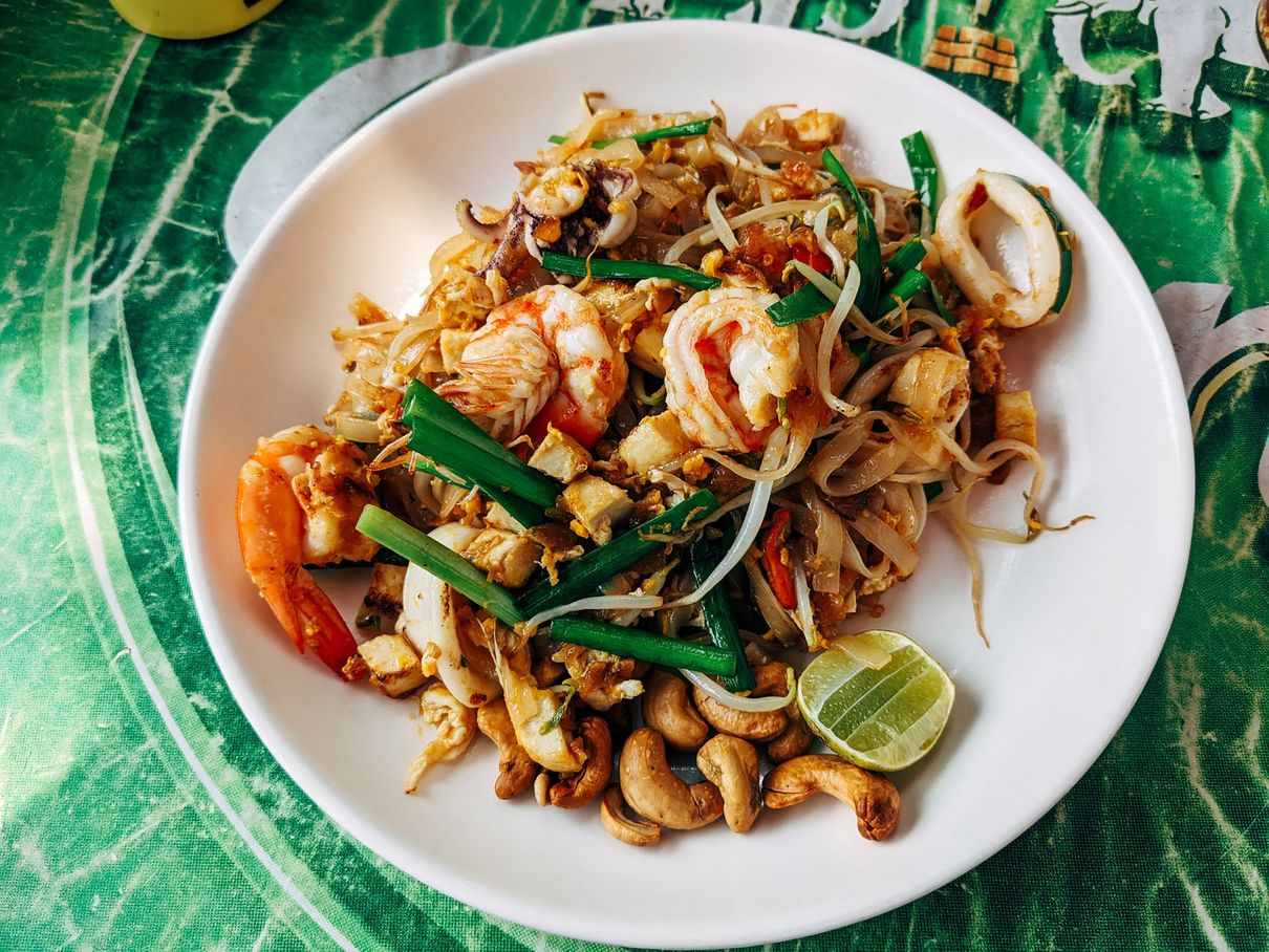 A plate of Thai food with shrimp and vegetables on a table