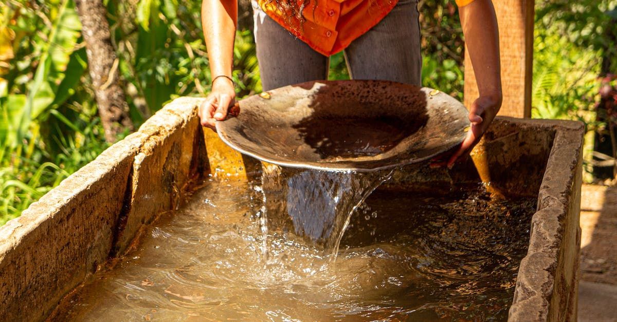 A woman is digging for gold in a bucket of water.