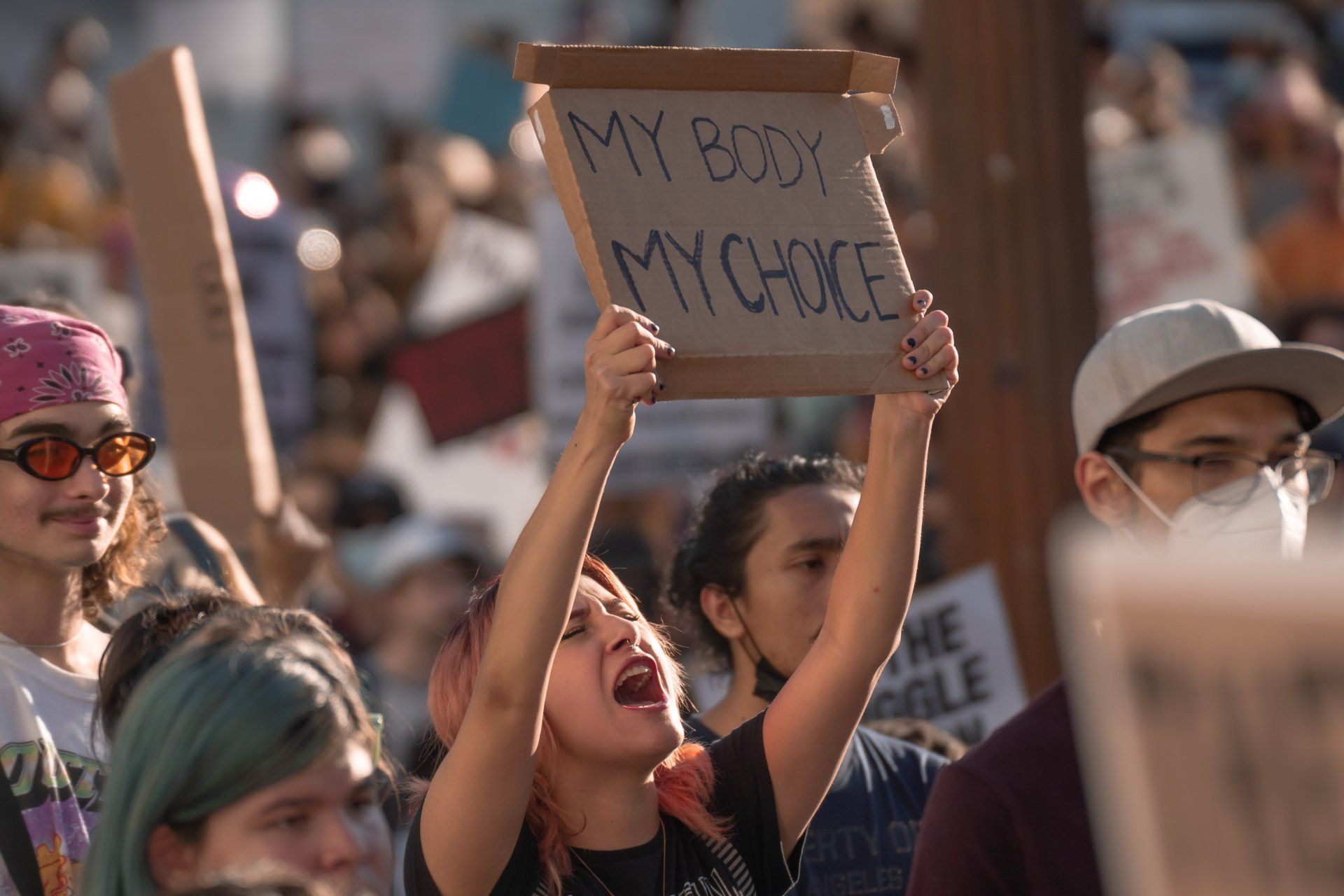A woman is holding a sign that says `` my body my choice '' at a protest.
