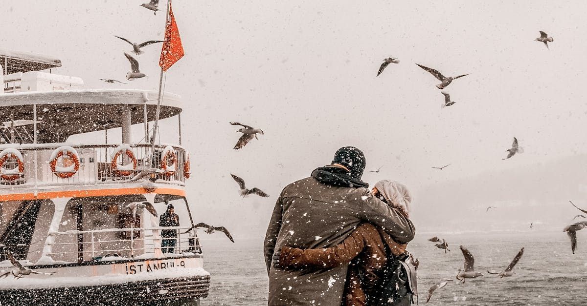 A couple is hugging in front of a boat in the snow.