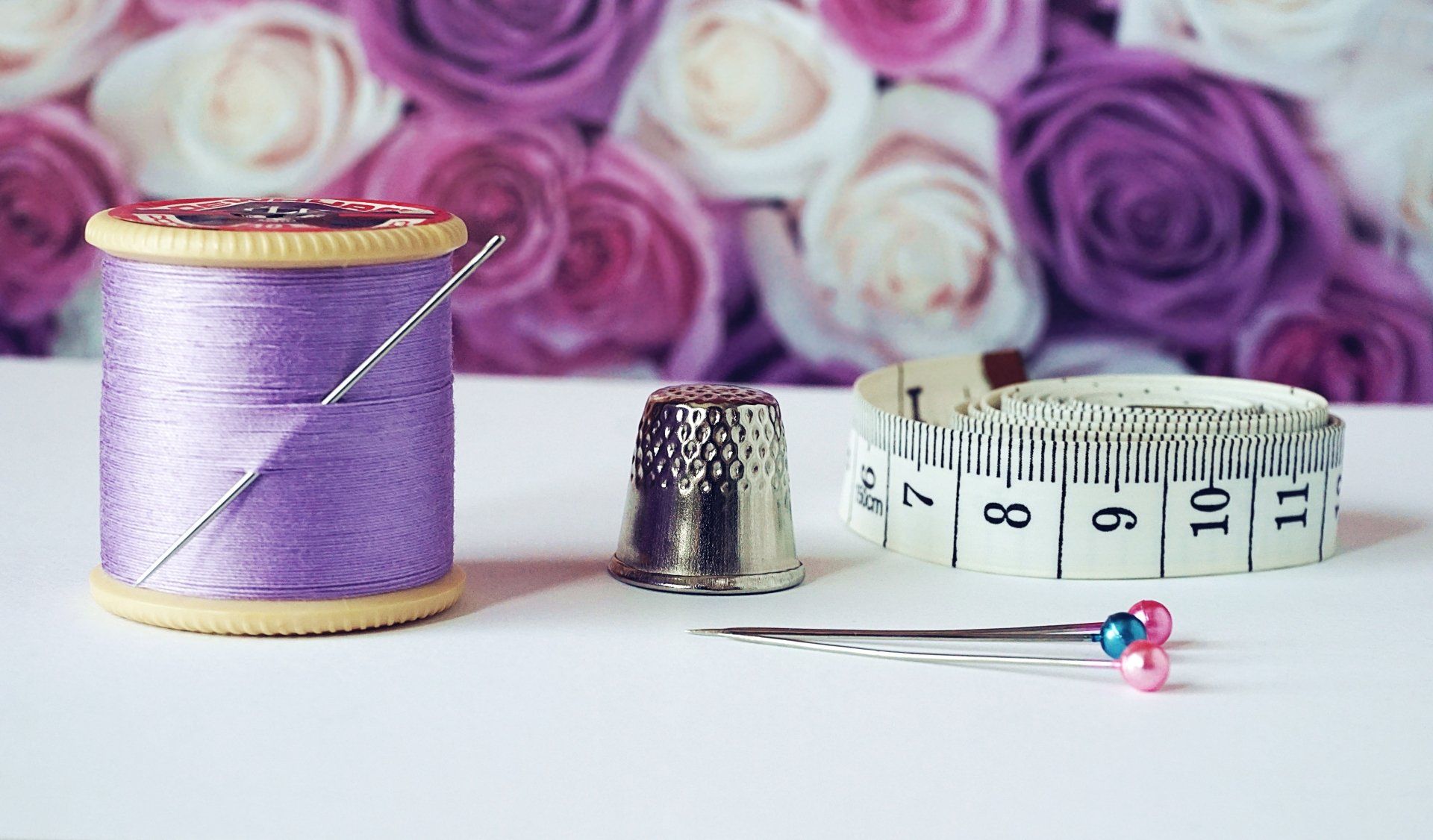 thread, thimble, pin, and tape measure with purple pink and white flowers for Community Open Sew events at Rachel Ann Quilts