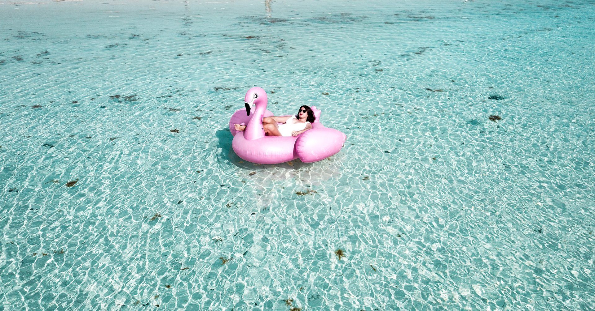 una donna galleggia su un fenicottero rosa nel mare