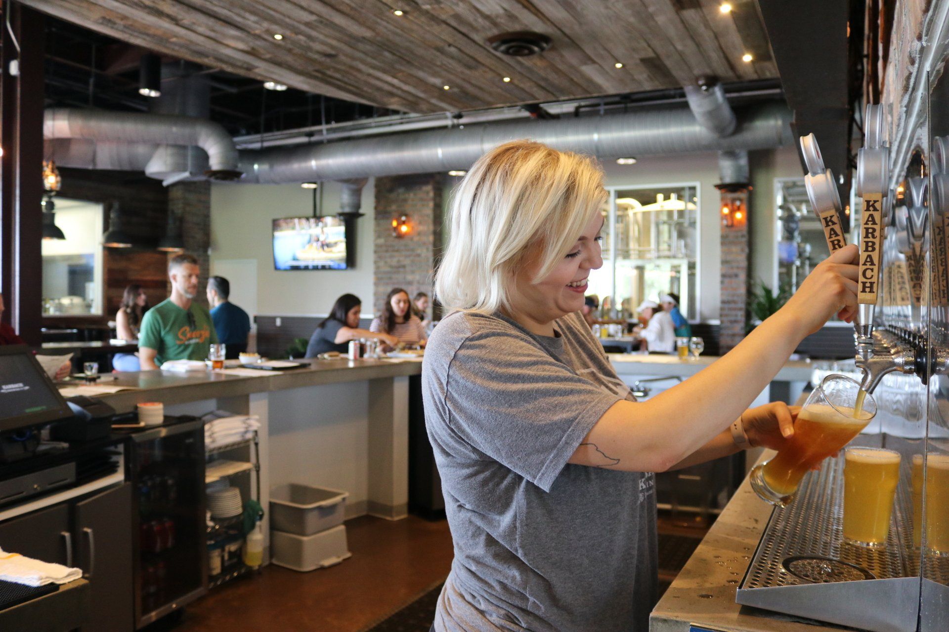 a woman is pouring beer from a tap in a restaurant .