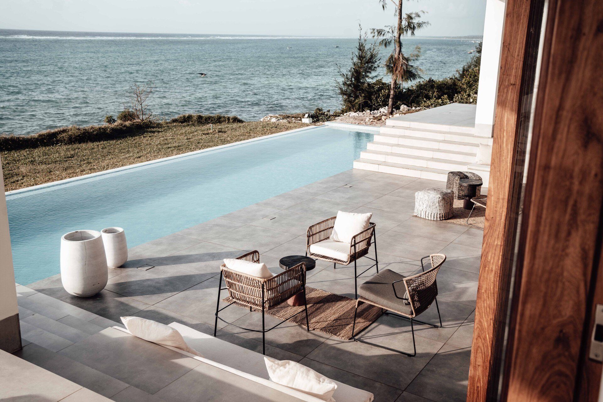 A patio with chairs and a swimming pool overlooking the ocean.