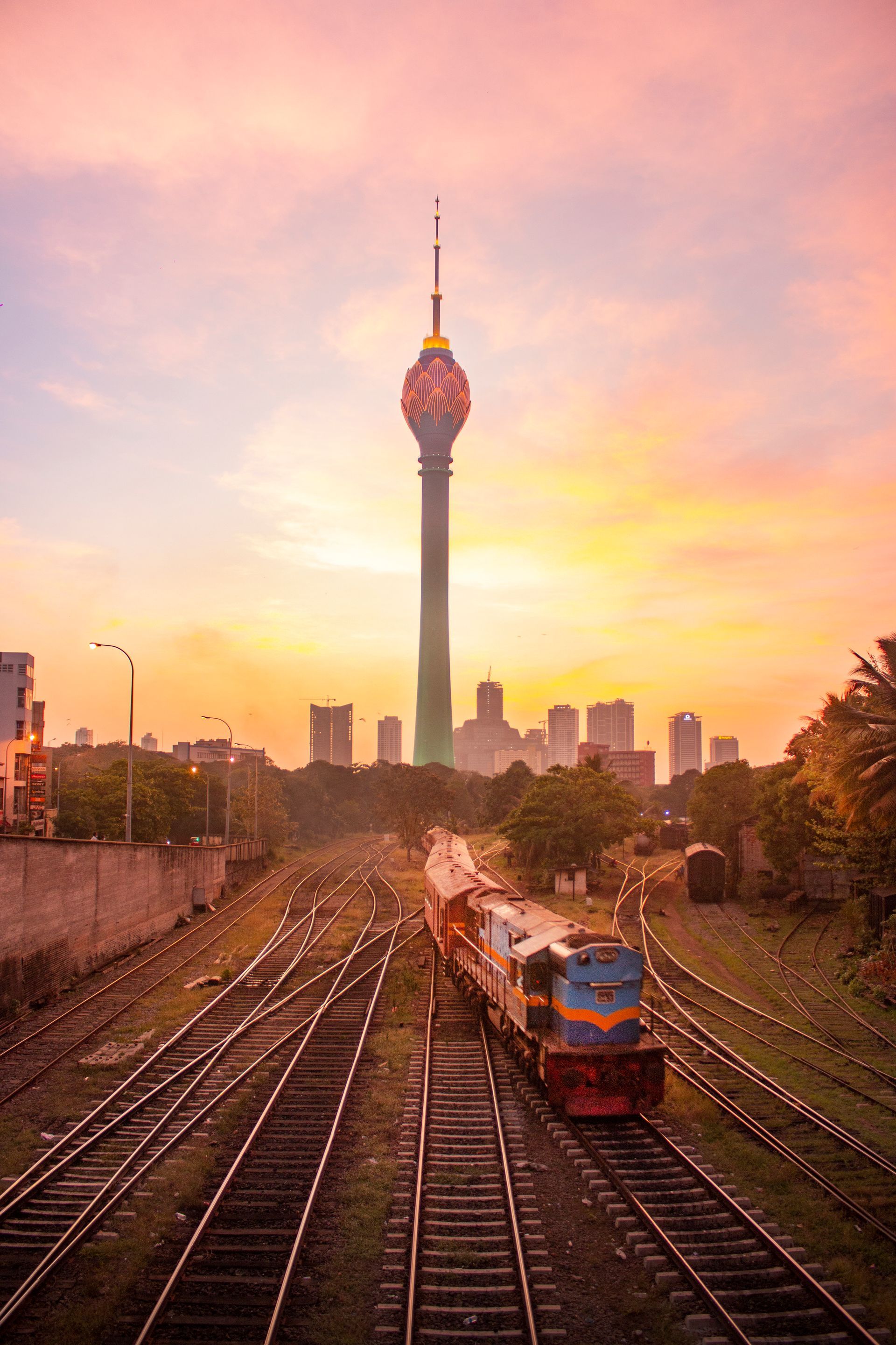 A train is going down train tracks with a clock tower in the background.