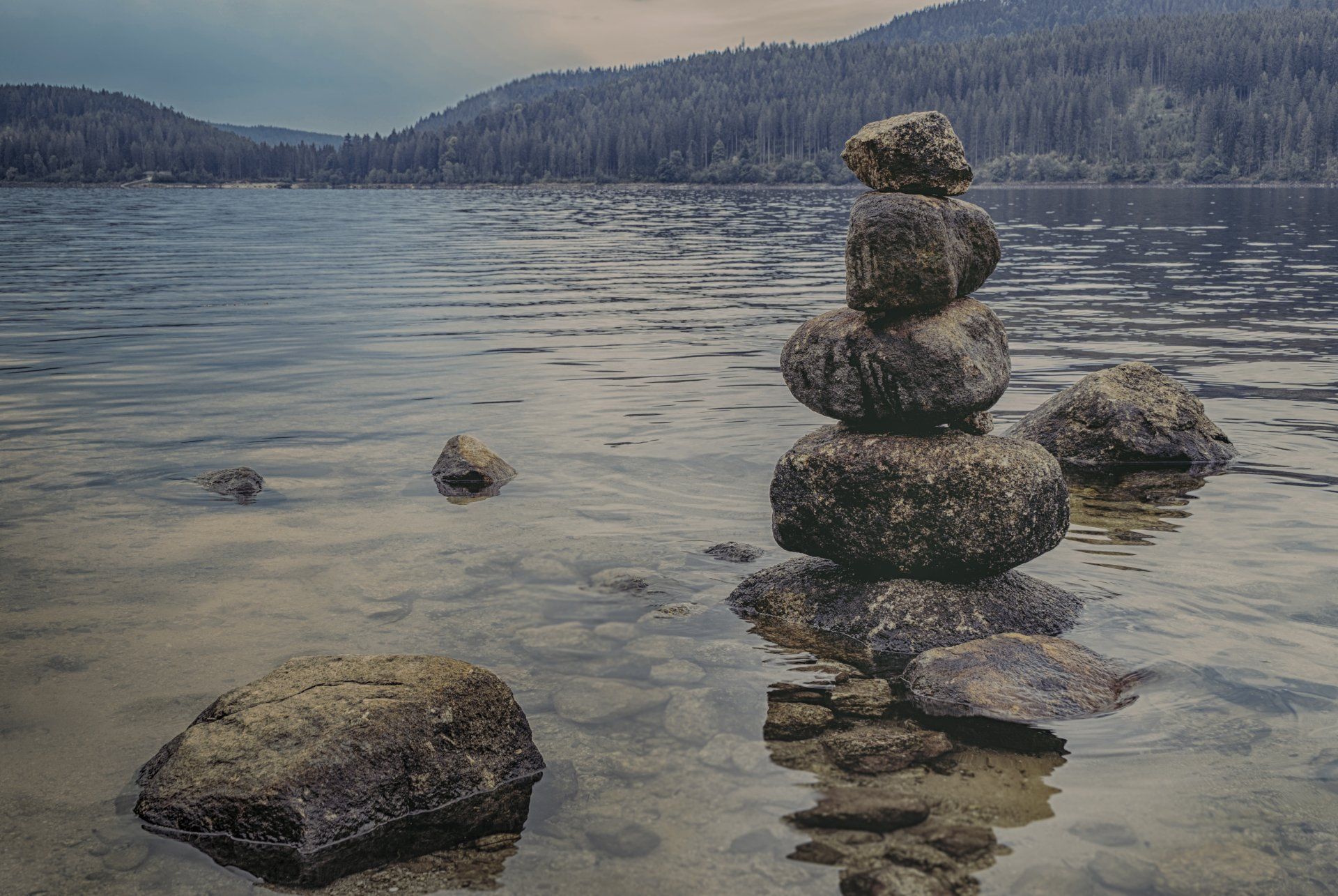 a pile of rocks stacked on top of each other on the shore of a lake .