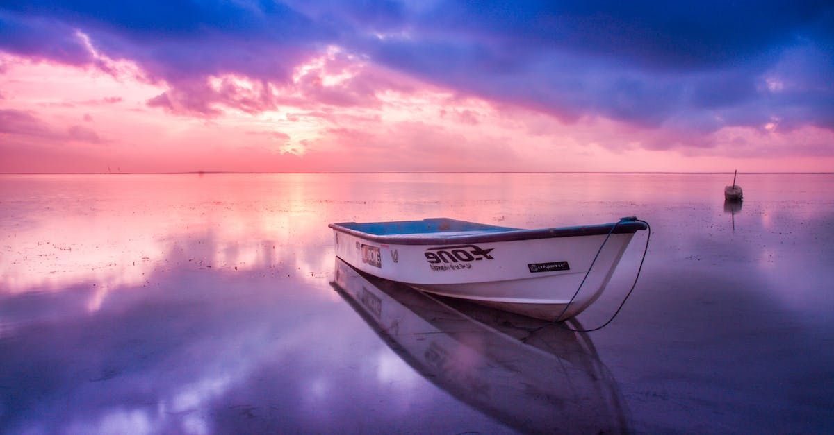 A boat is floating on top of a body of water at sunset.