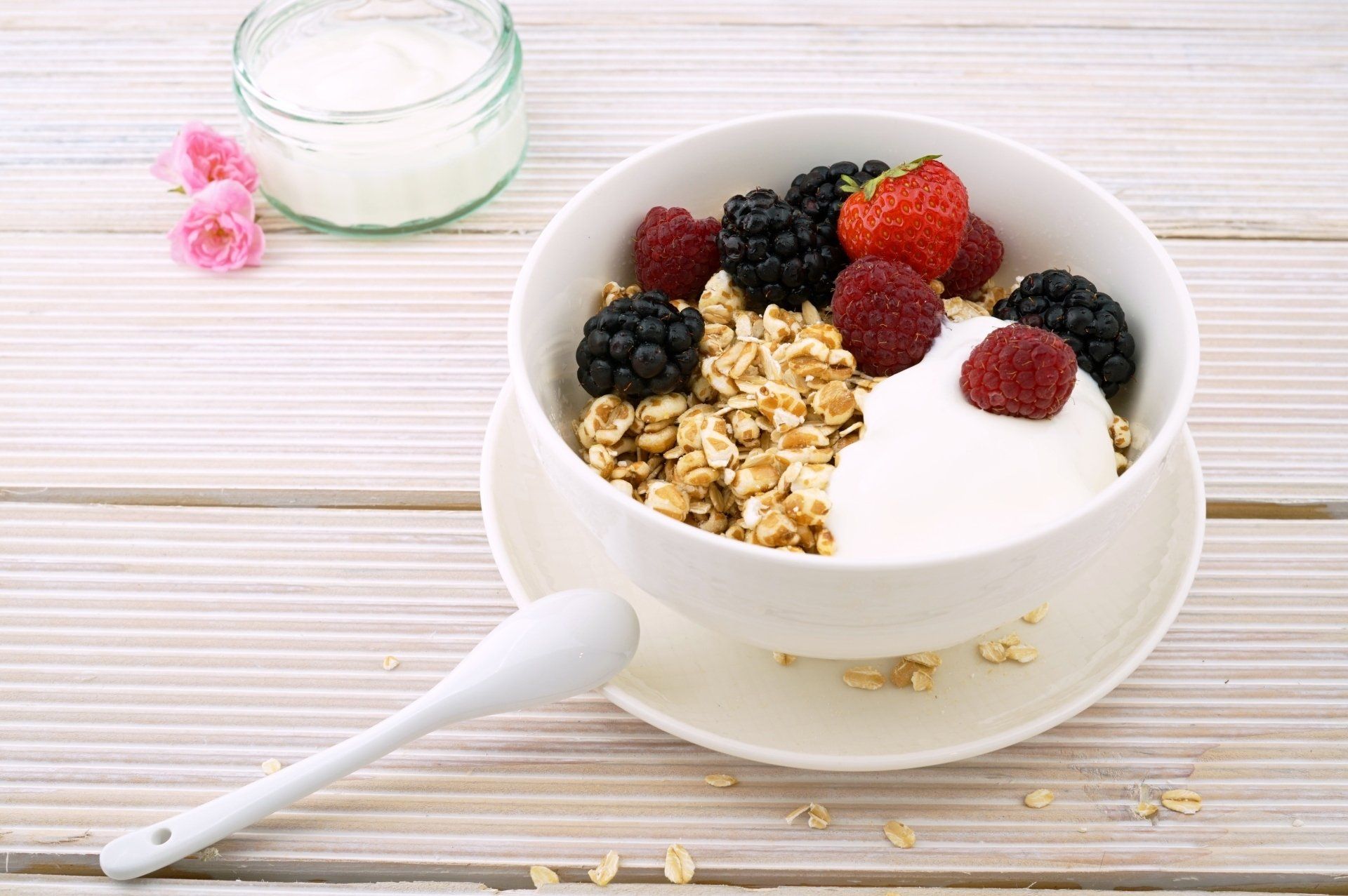 A bowl of oatmeal with berries and yogurt on a wooden table.