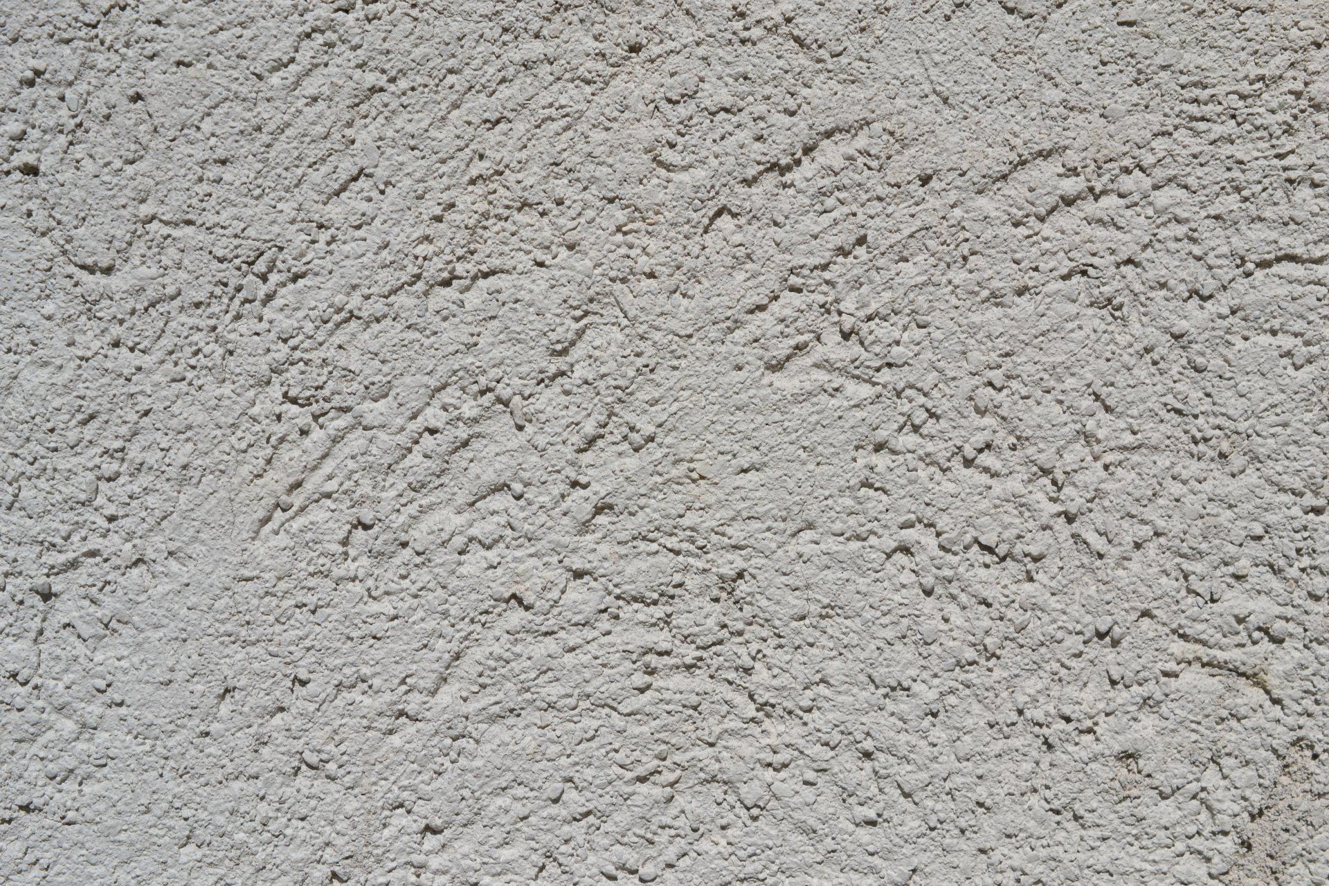 Close-up of a stucco wall undergoing repair with a gravel texture.
