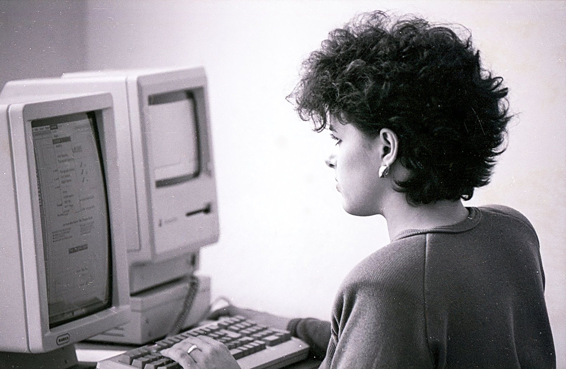 uma foto em preto e branco de uma mulher usando um computador