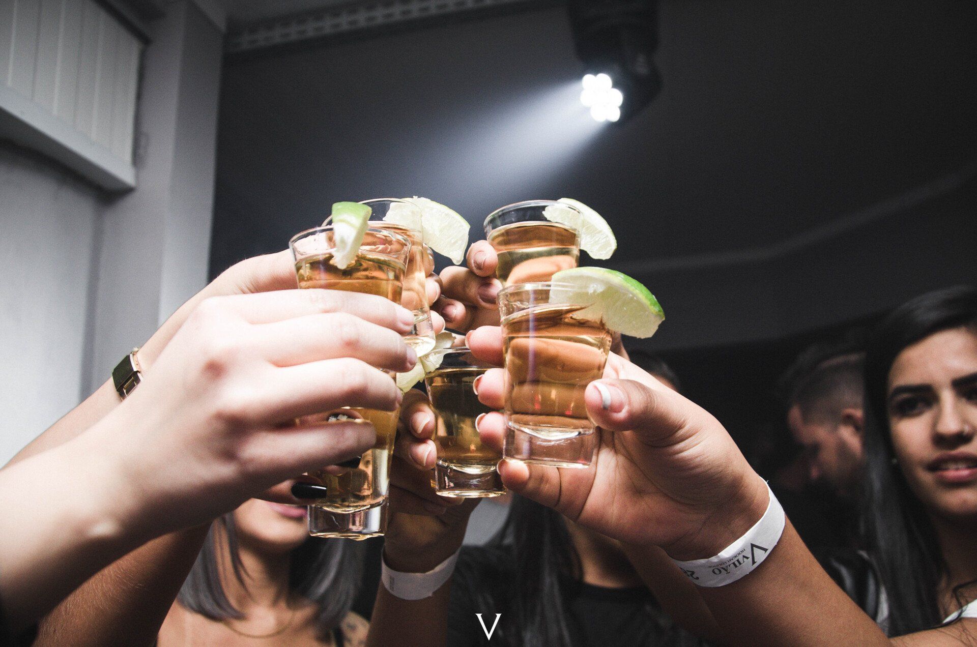 A group of people are toasting with shot glasses of tequila.