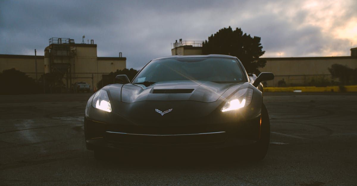 A black sports car is parked in a parking lot at night.