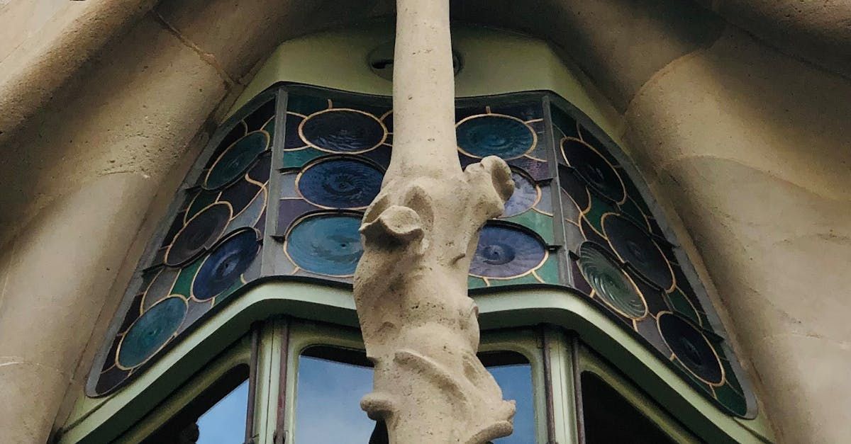 A statue of a tree is hanging from a window on a building.