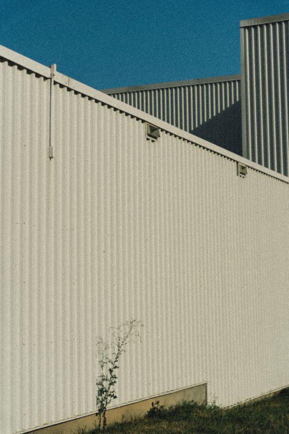 A white fence surrounds a building with a blue sky in the background.