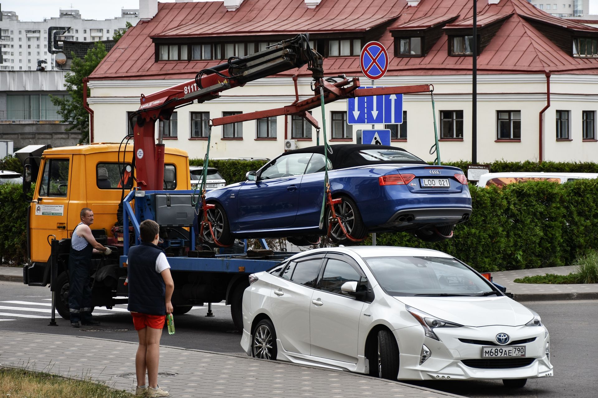 A blue car is being towed by a tow truck.