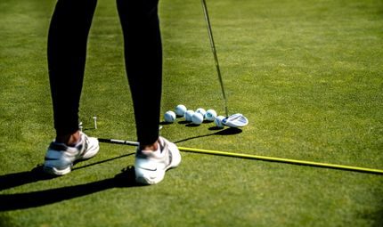 A person practicing putting at a driving range.