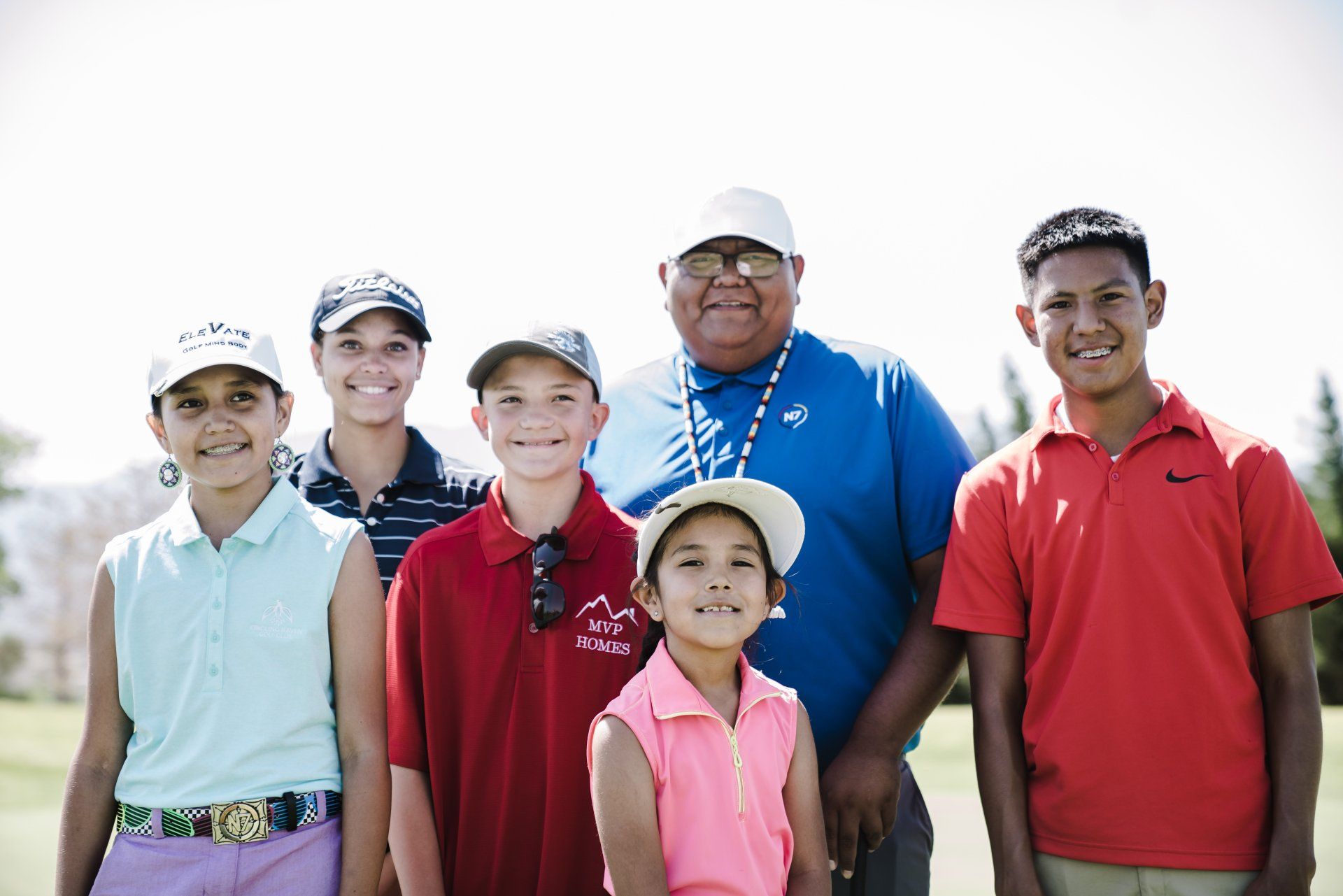 a group of children and a man are posing for a picture on a golf course .