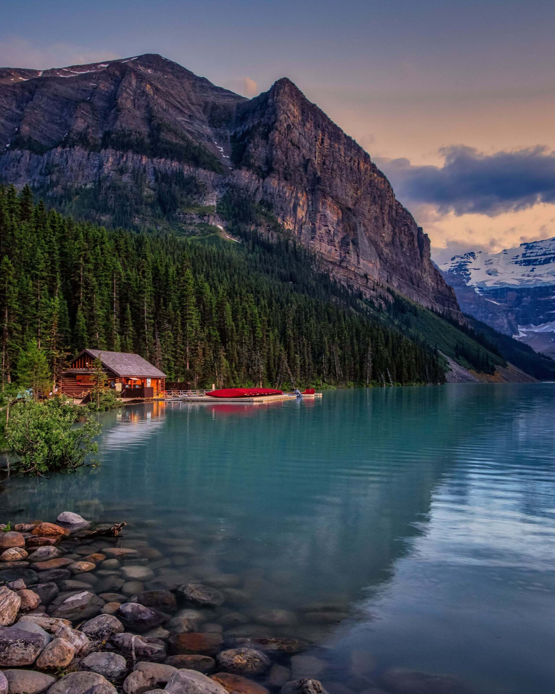 A lake surrounded by mountains and trees with a reflection of the mountains in the water.