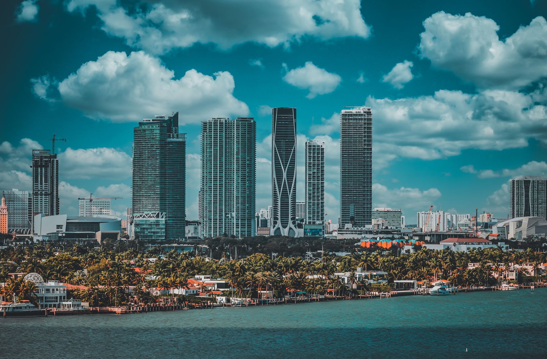 A city skyline with a lot of tall buildings and a body of water in the foreground.