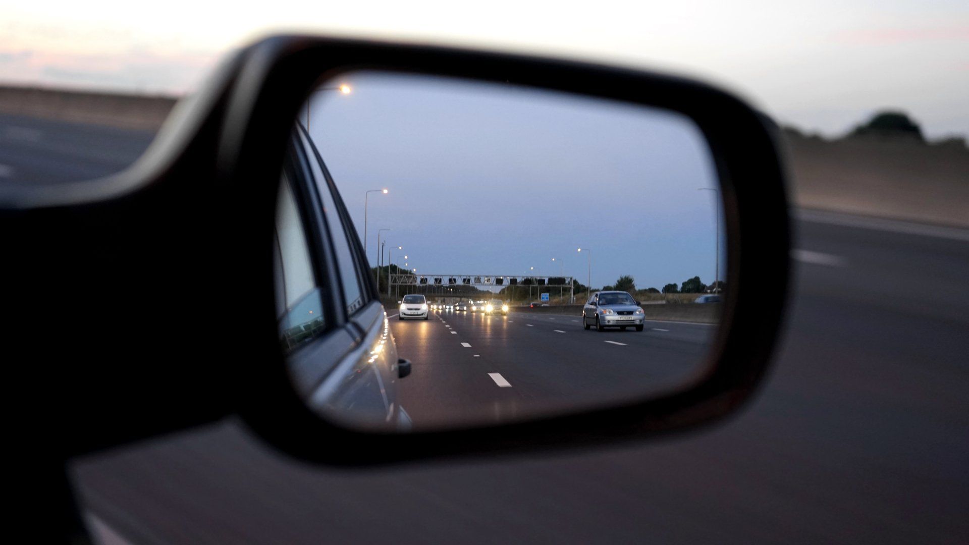 a car is driving down a highway in the rear view mirror