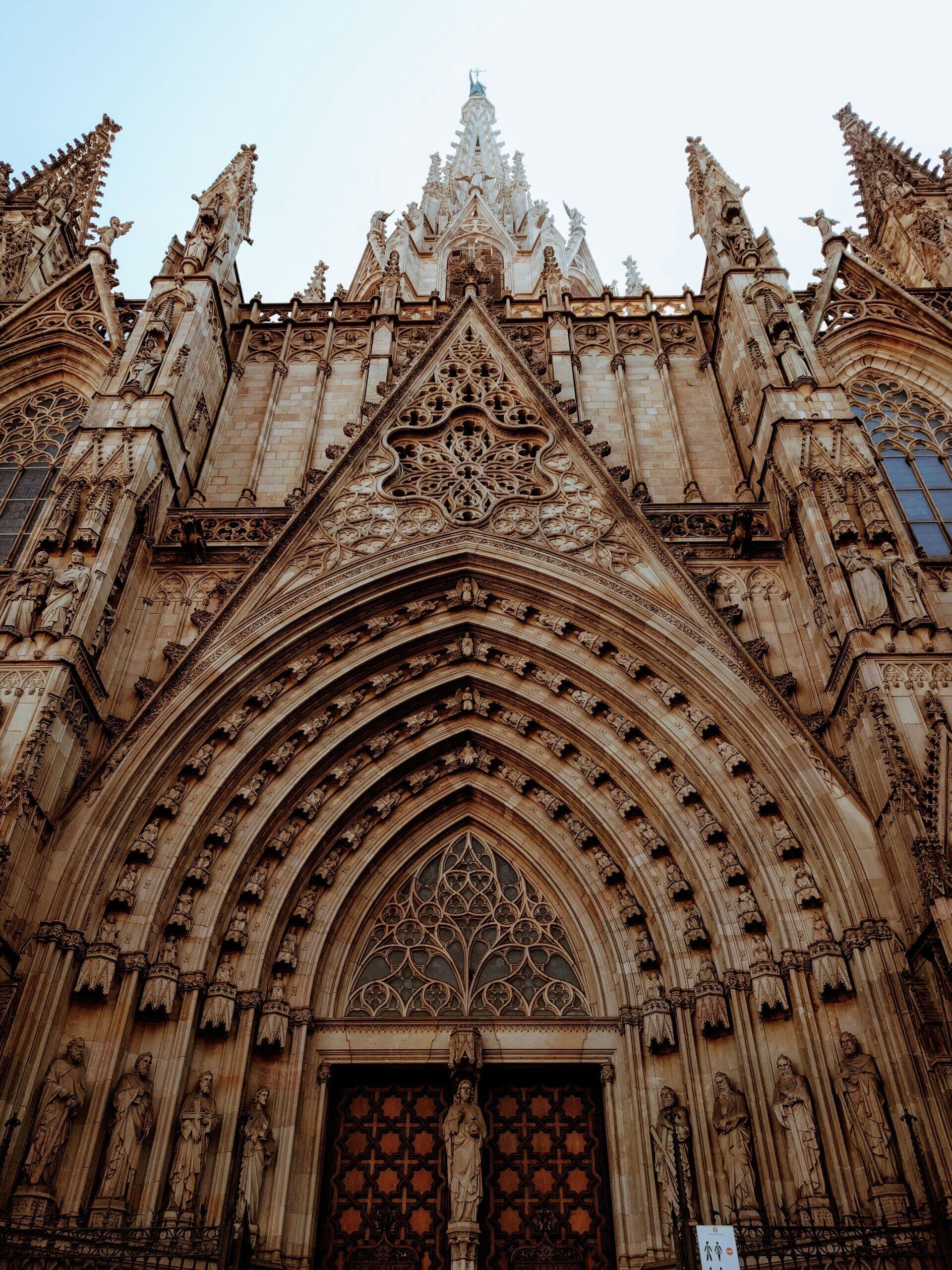 The front of a large medieval cathedral with a statue of jesus on the door.