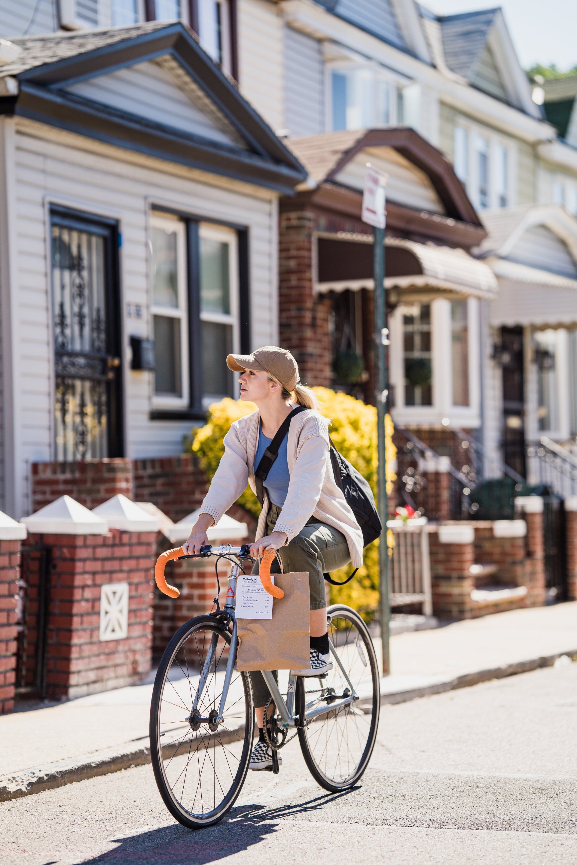 A woman is riding a bike down a street with a cardboard box in her basket.