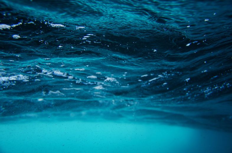 A close up of a body of water with waves and bubbles coming out of it.