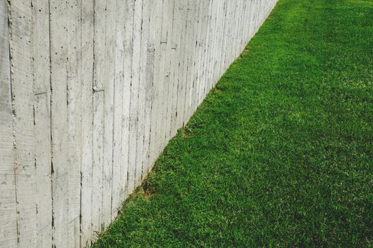 A concrete fence surrounds a lush green lawn.