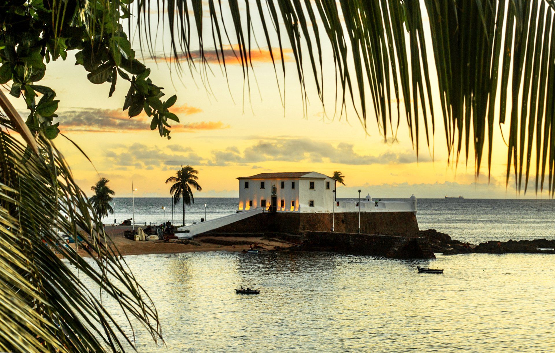 A small island in the middle of the ocean with a palm tree in the foreground.