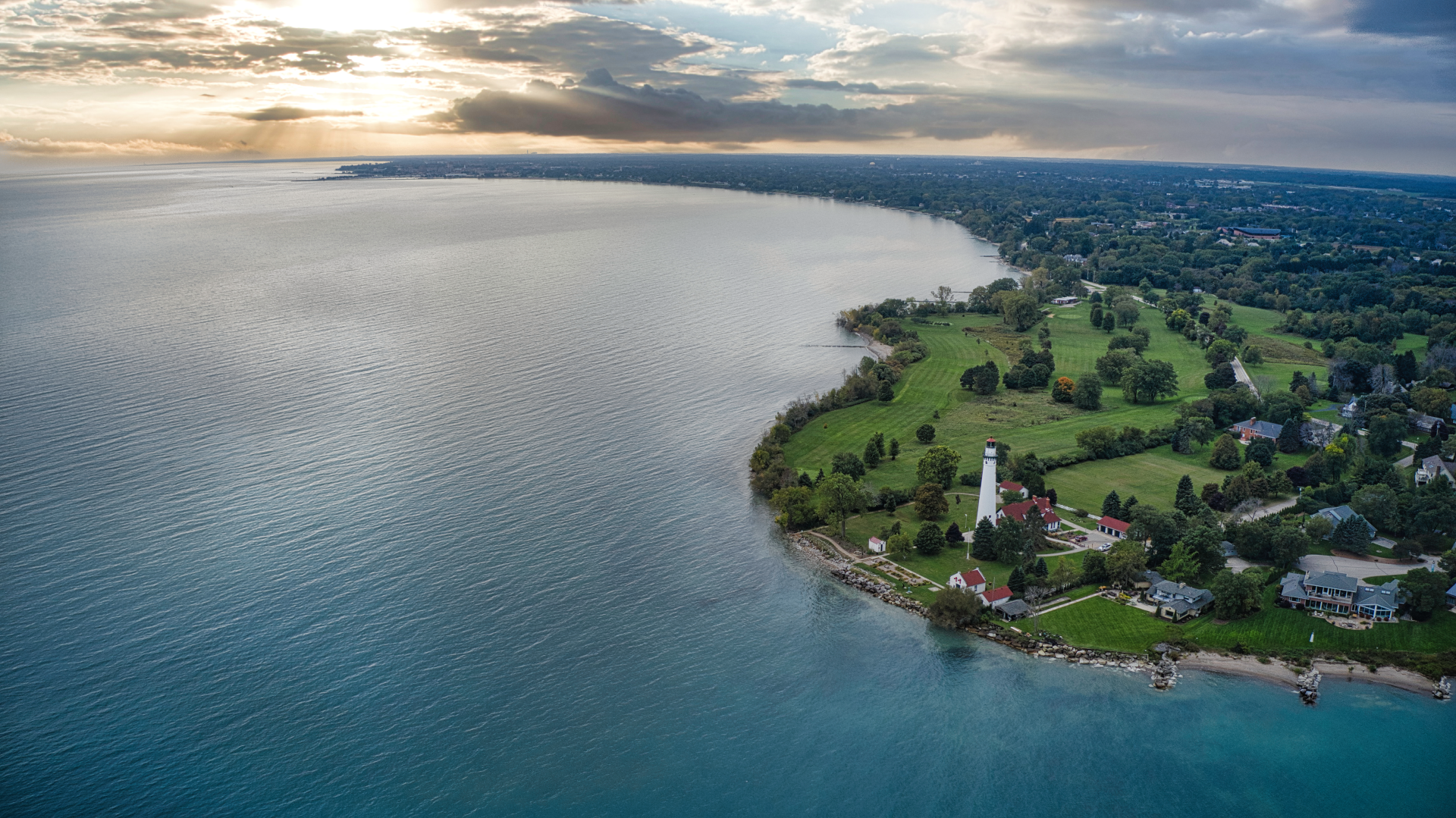 An aerial view of a lake with a lighthouse on the shore.