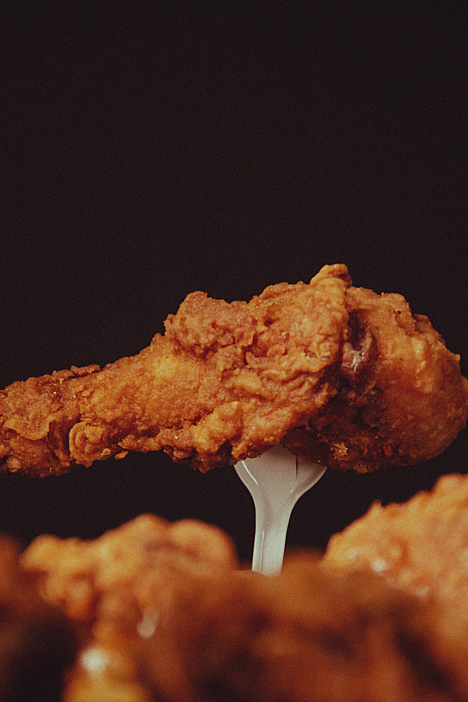 a close up of a piece of fried chicken on a fork .