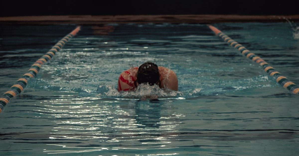A person is swimming in a swimming pool at night.