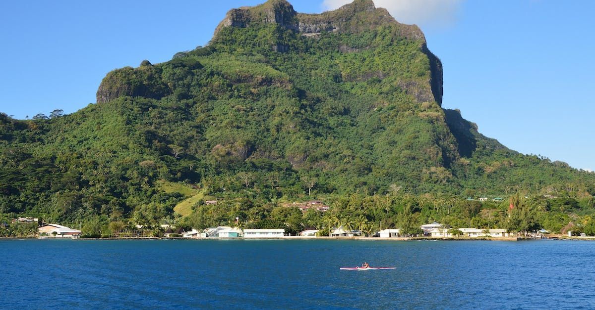A large mountain is surrounded by trees and a body of water.