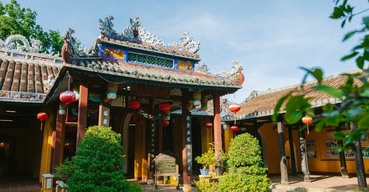 A chinese temple with lanterns and trees in front of it.