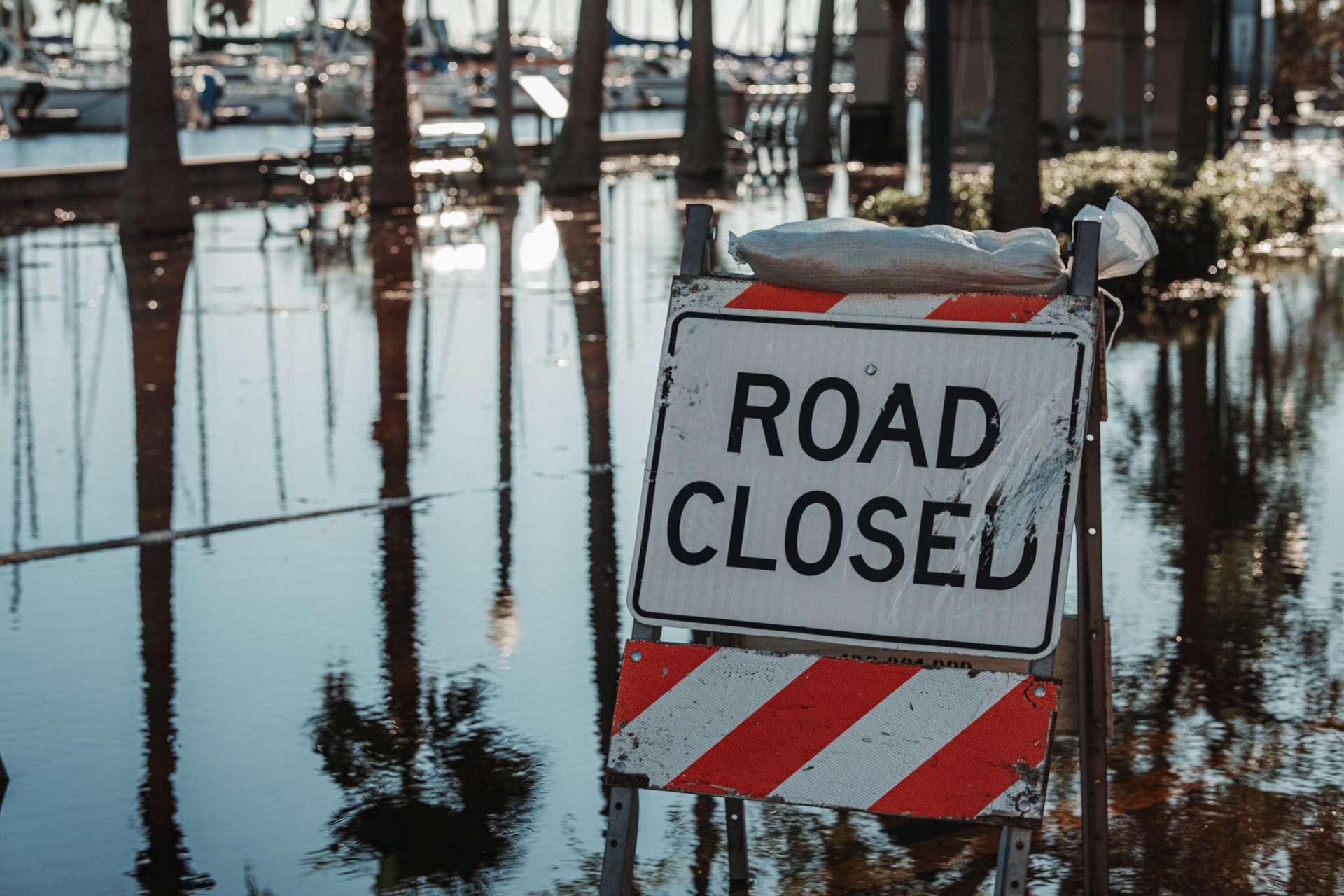 A road closed sign is sitting in the middle of a flooded area.