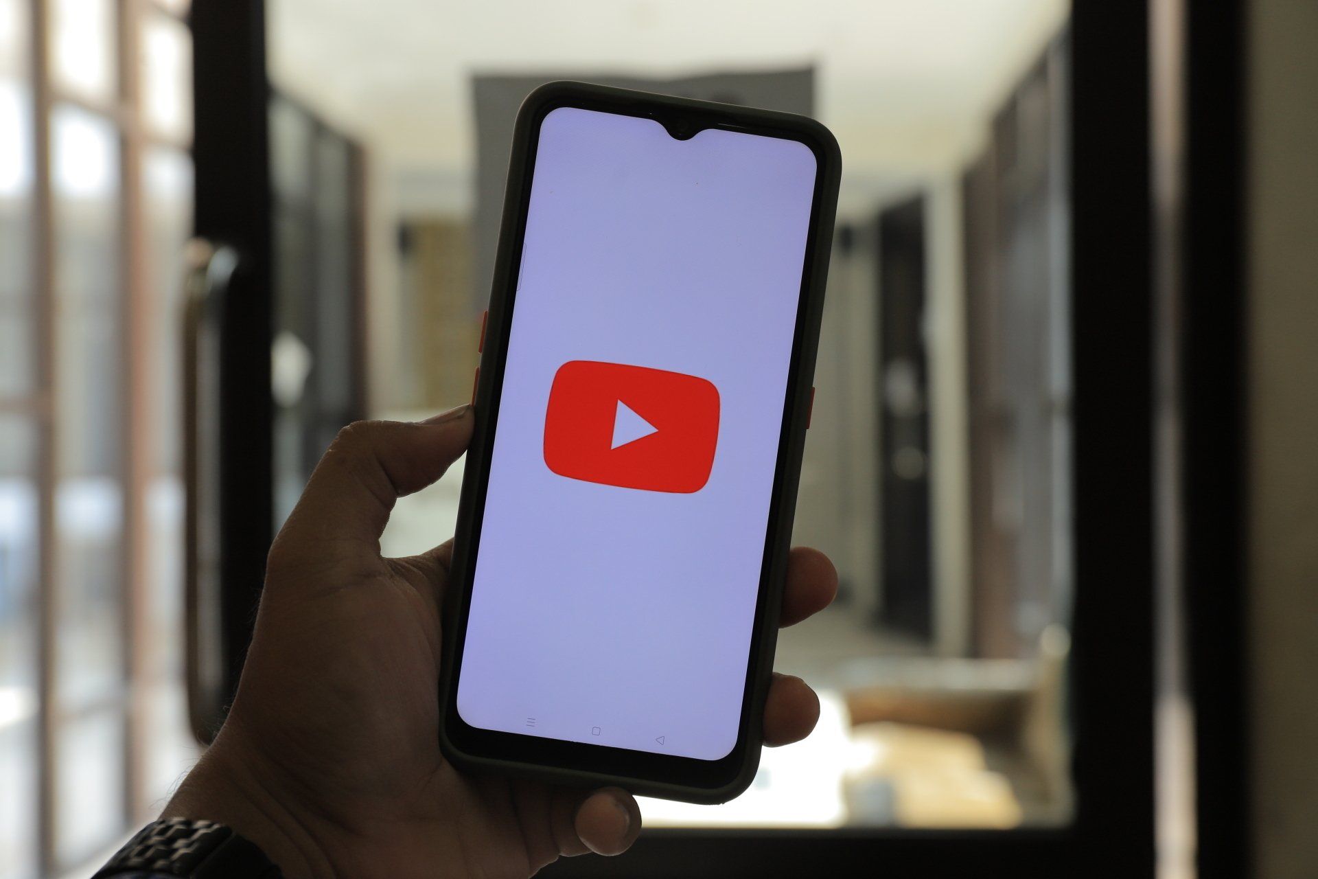 A person is holding a cell phone with a youtube logo on the screen.