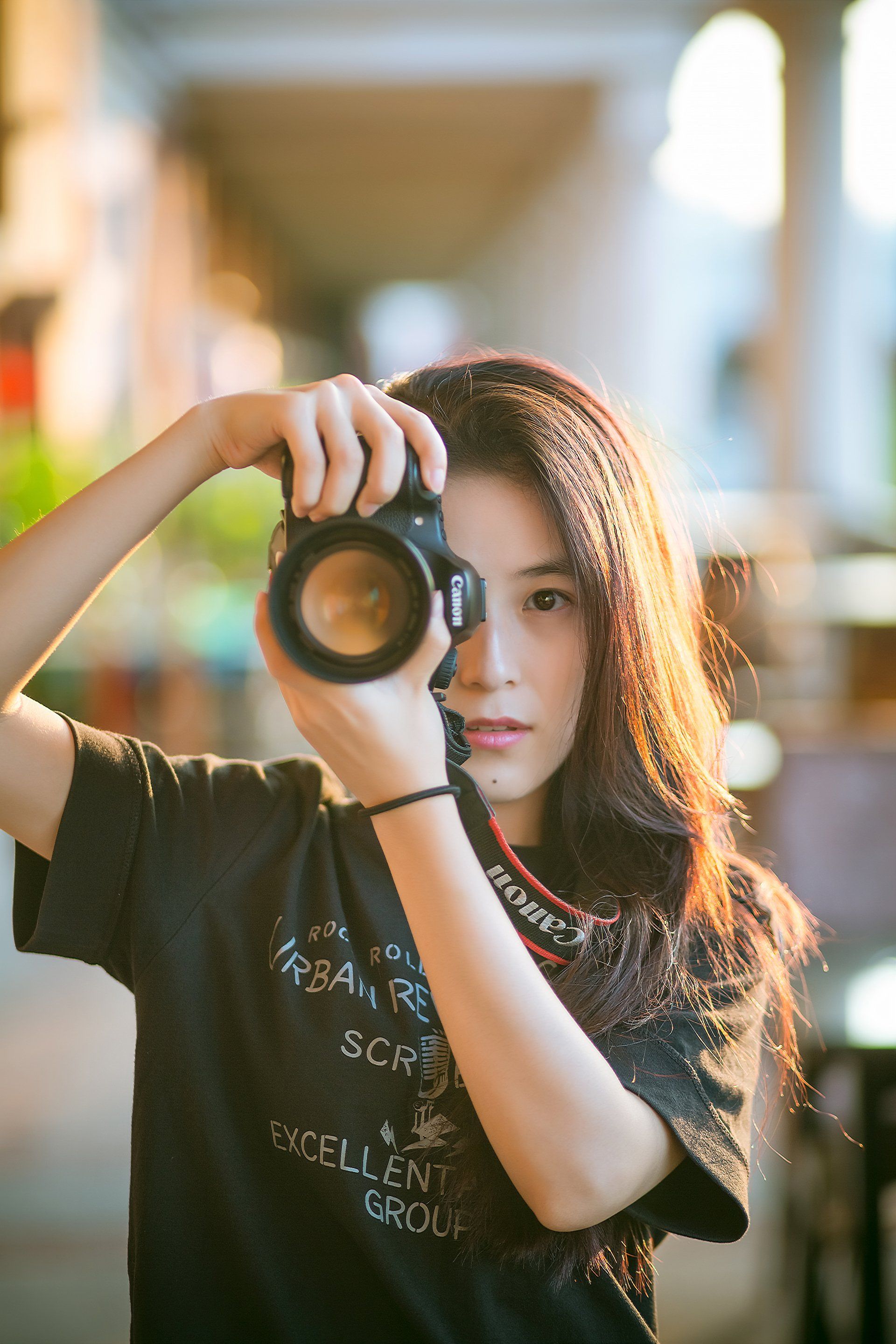 Picture of an Asian woman holding a digital camera to her face, taking a picture